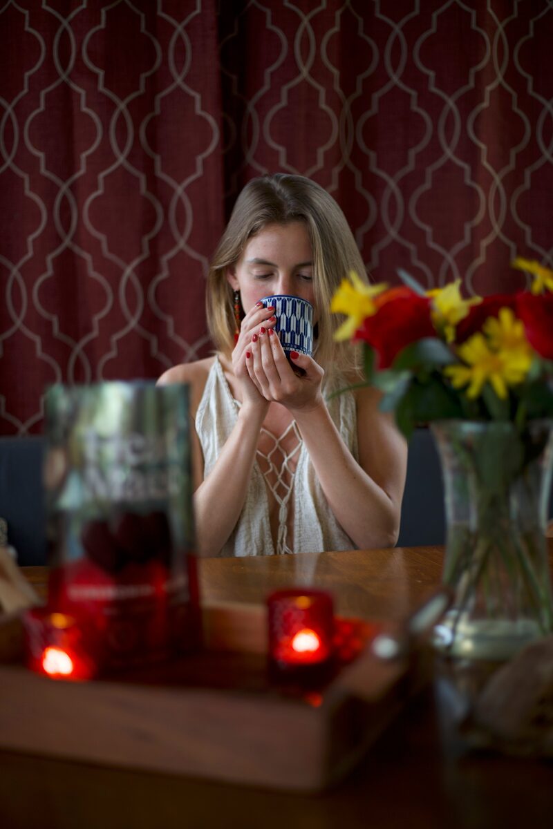 Woman closing her eyes and smiling while savoring a warm mug of cacao at home