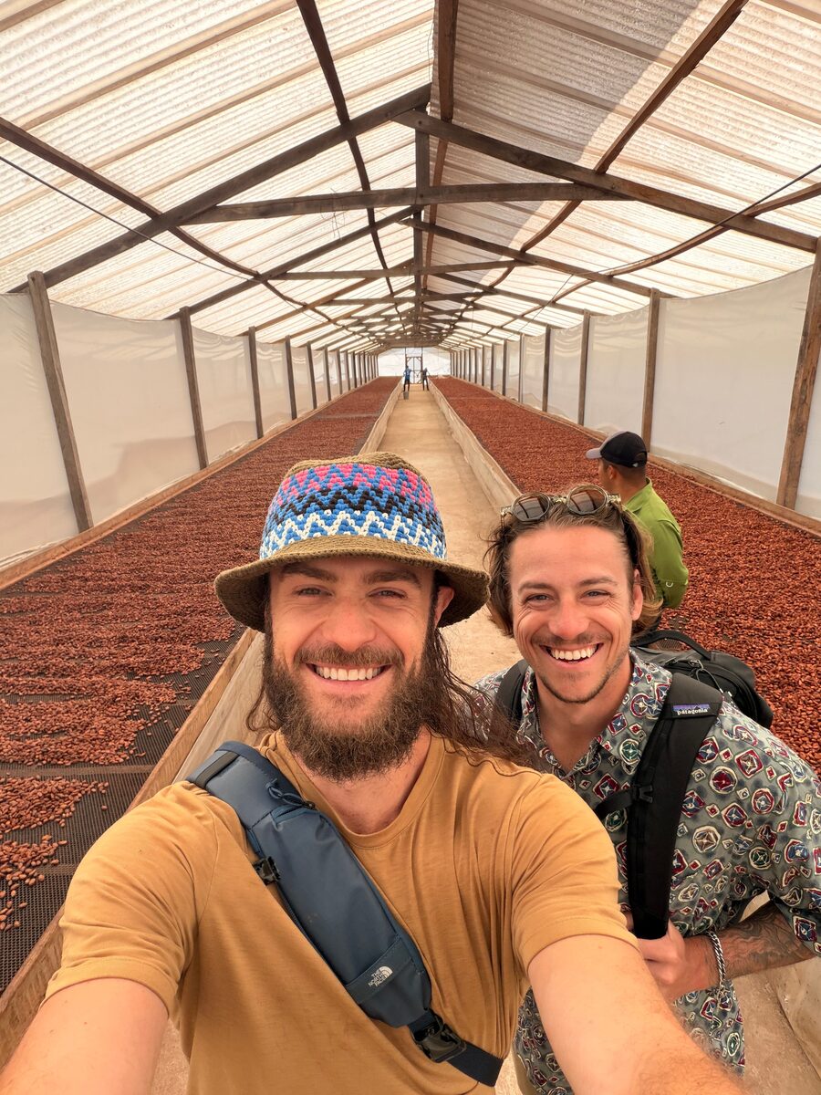 Jacob and Marco laughing together inside a cacao drying house in Guatemala